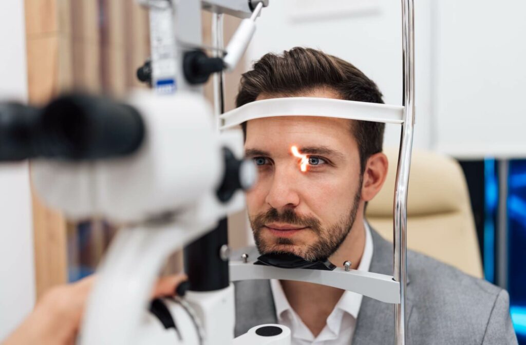 A patient wearing a suit undergoing a slit lamp exam during their routine eye exam to detect any potential diseases.