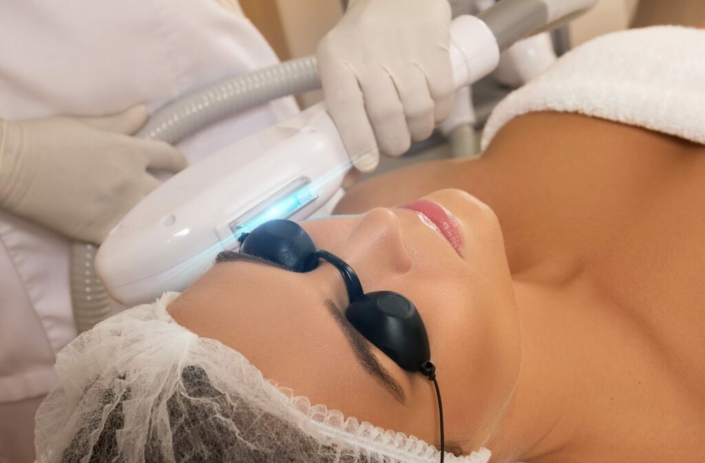 A woman wearing protective goggles receiving IPL treatment for dry eye, with a specialized device being applied around her eyes.