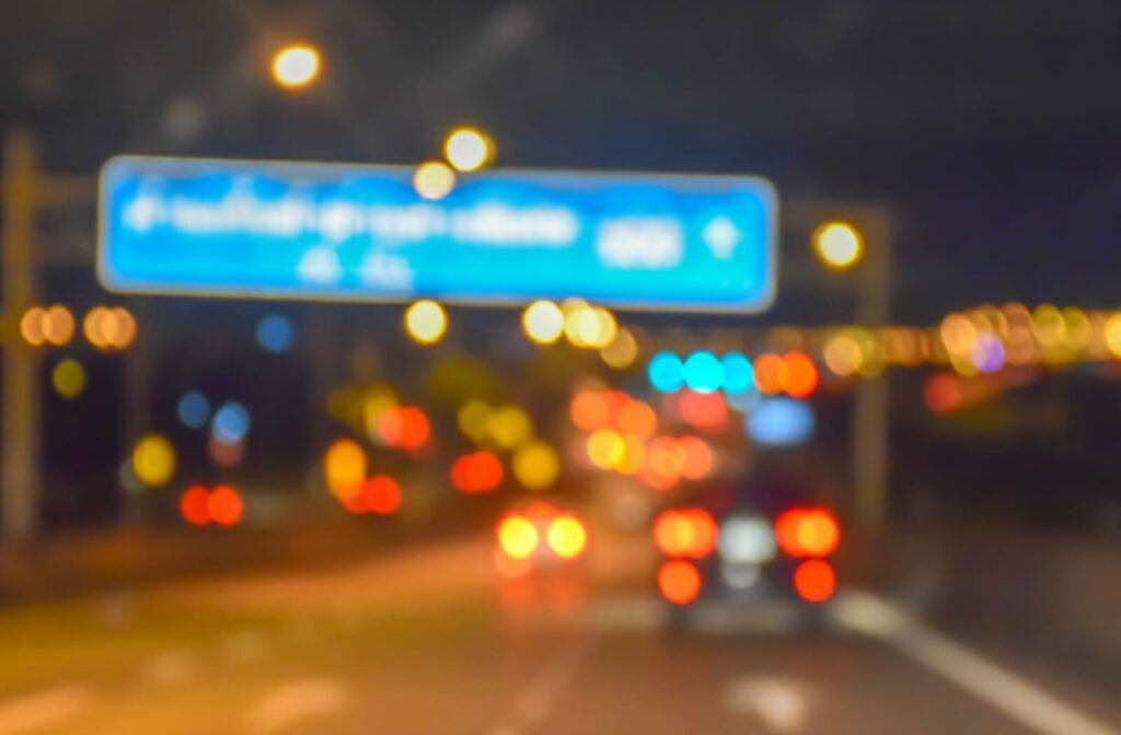A busy road is shown at night. The effects of dry eye leave the scene looking blurry and distorted.