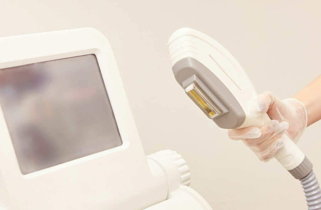 An IPL machine sits in front of a beige background, while a person holds up the head of the machine.
